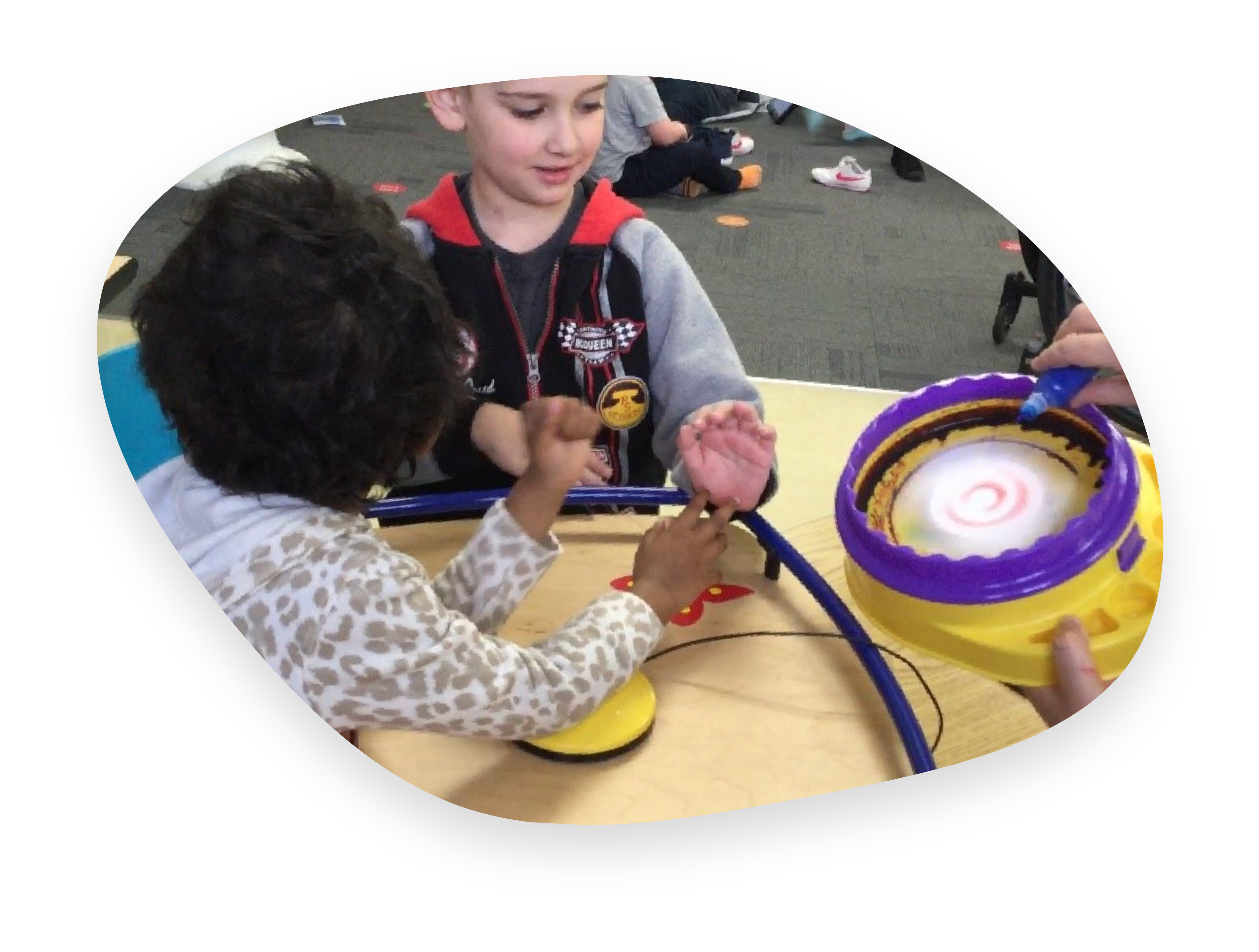 Two students participate in a painting activity using a spinner.