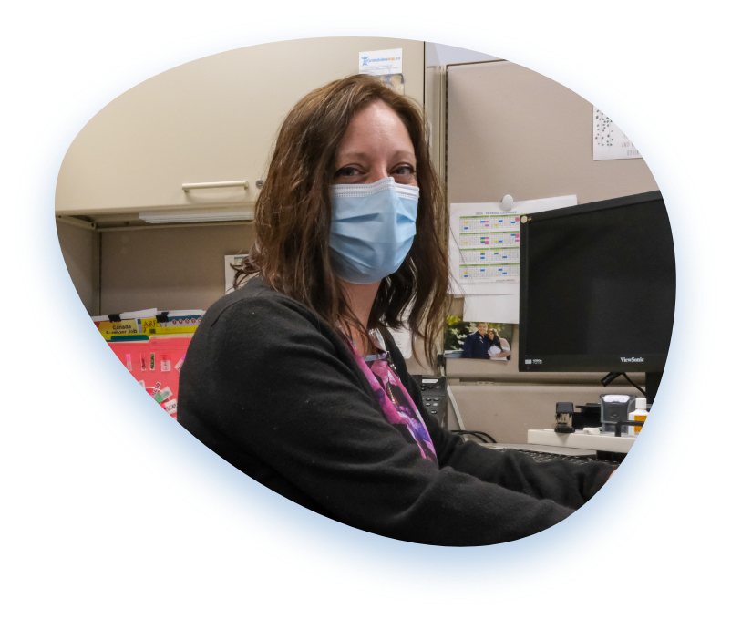 A member of Team Grandview smiles at the camera while wearing a medical mask.