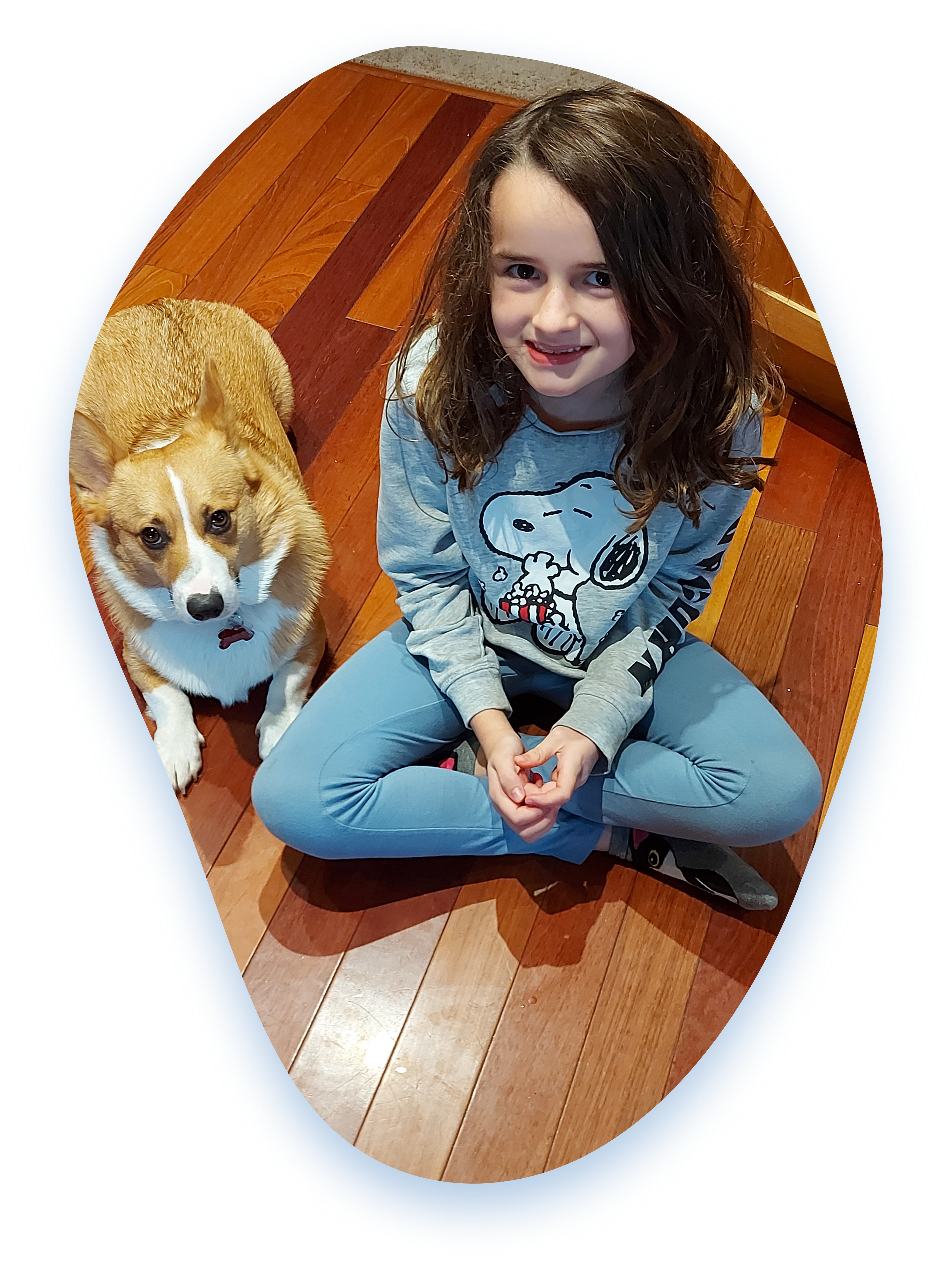 Grandview Kid, Zayla, sits cross-legged on the floor with her pet dog.